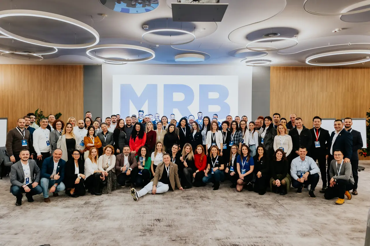 Fotografia de grup a participanților MRB 2025, în fața ecranului cu logoul MRB