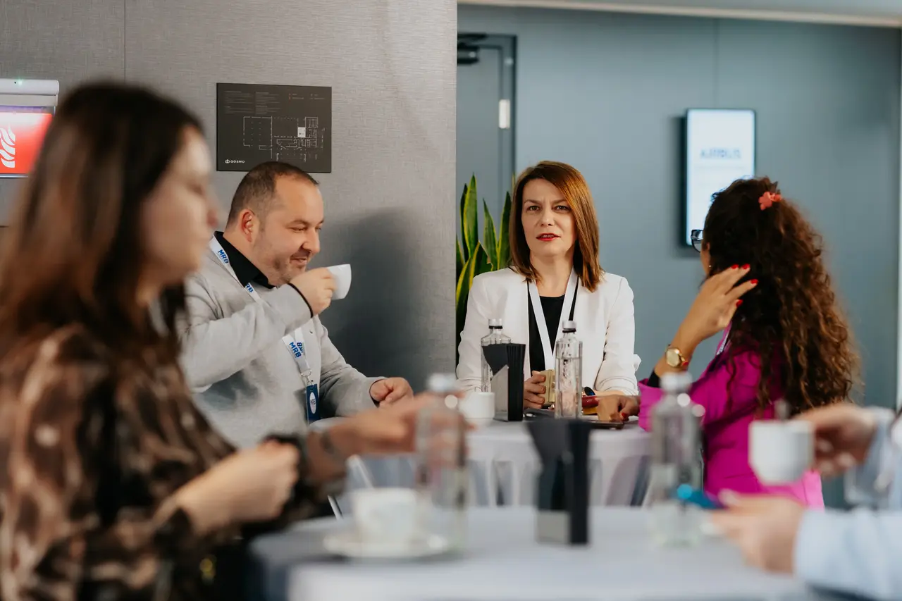 Participanți la cafea în conversație la mese înalte, MRB 2025