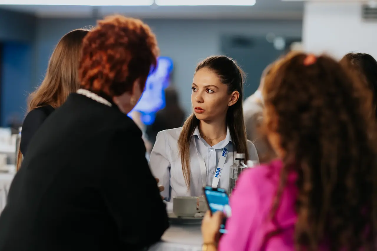 Participante discutând în pauză lângă o masă înaltă, MRB 2025