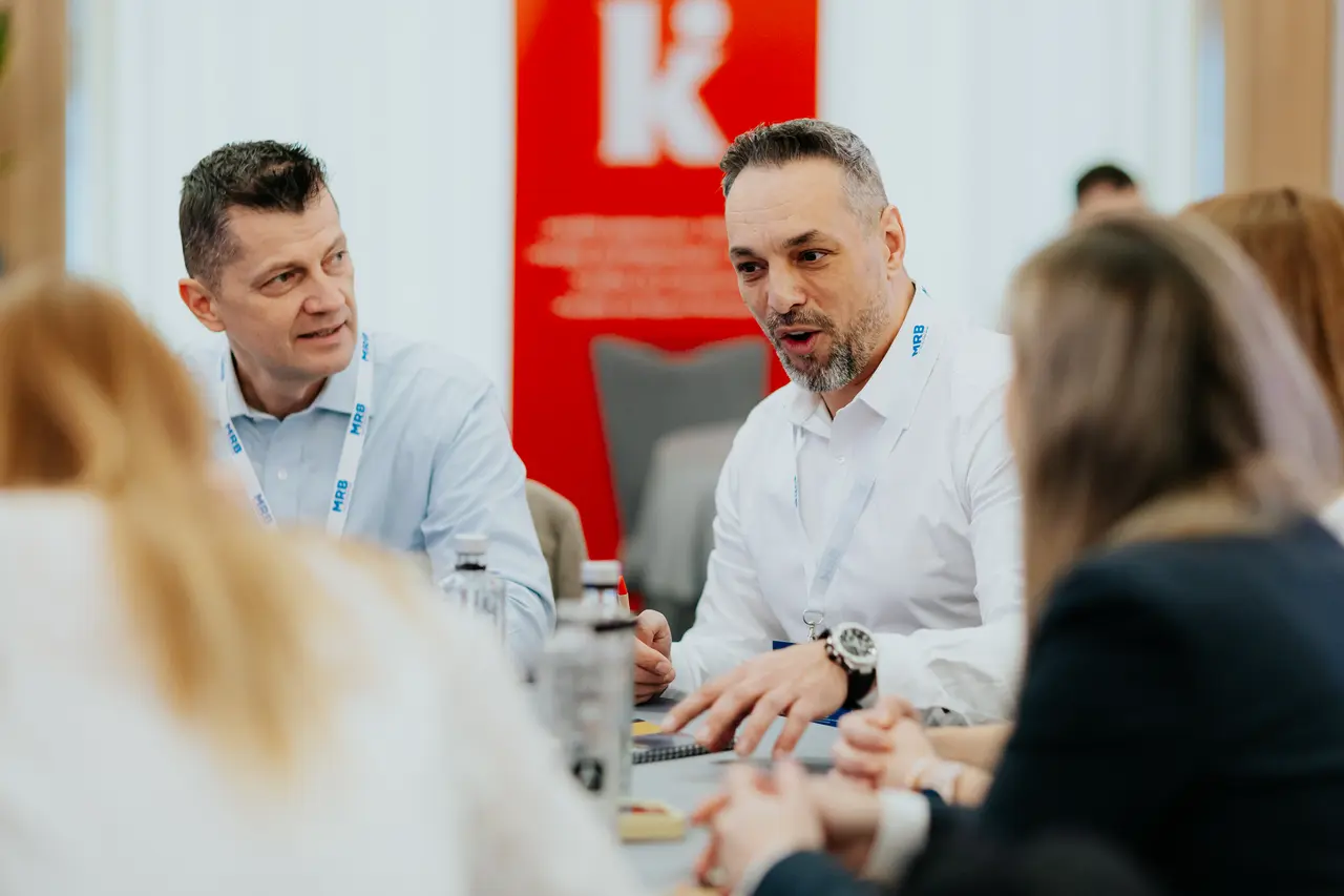 Doi participanți în conversație la masă, MRB 2025